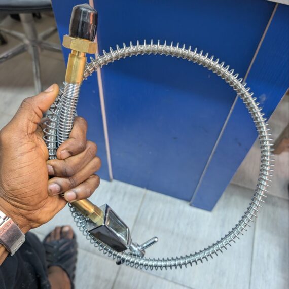 Metal braided medical oxygen delivery hose with external spring guard and clamp-style connector.